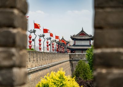 a view of a wall with flags and buildings in the background